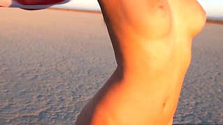 Curvy petite brunette strips at a beach