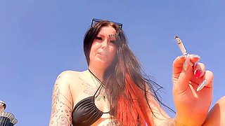 Smoking fetish. Dominatrix smokes a cigarette on the beach