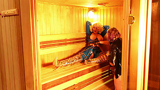 Bondage process in the sauna: sexy gagged submissive MILF in latex and her rubber dominatrix